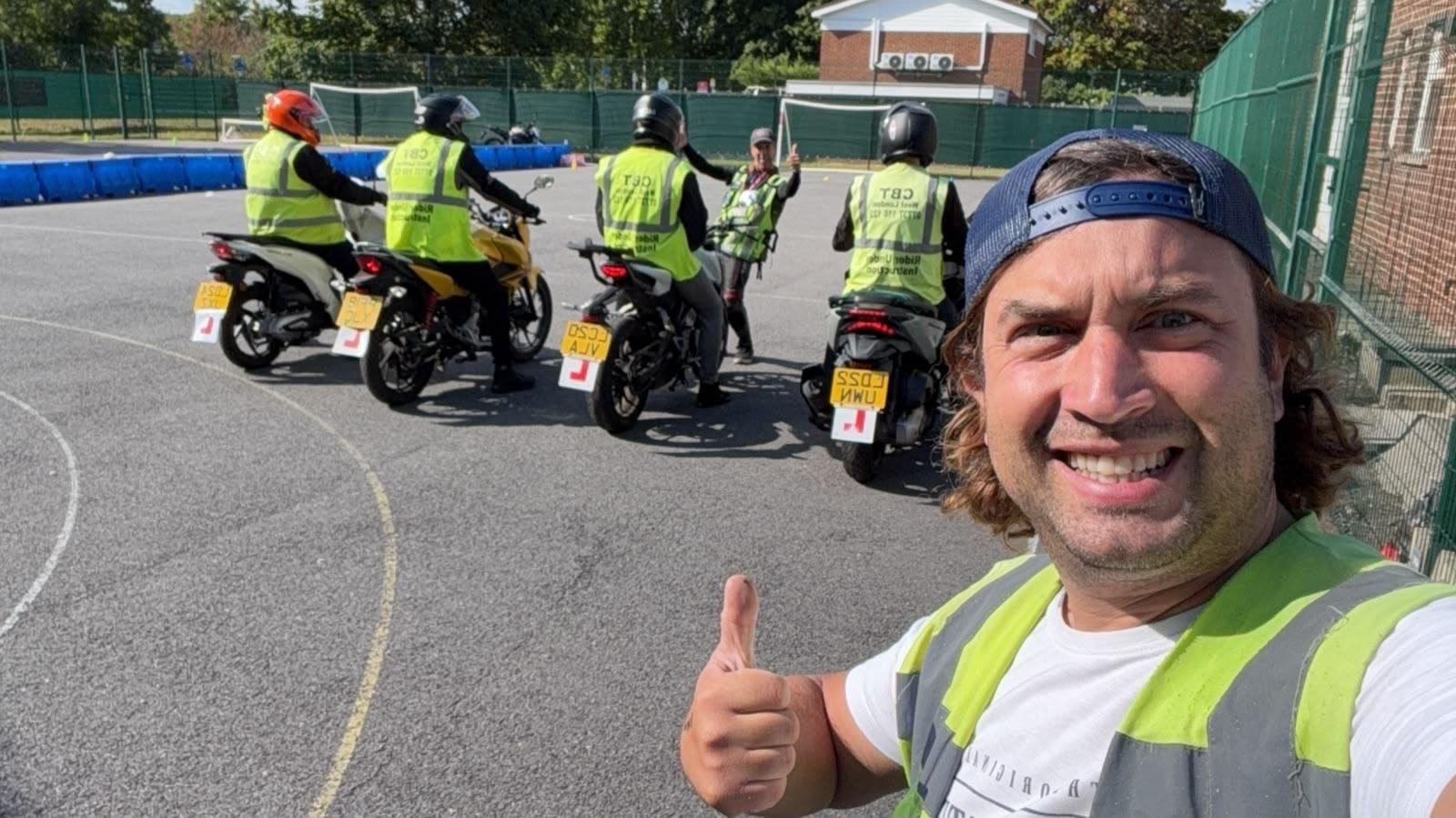 CBT West London instructor giving a thumbs up with a group of riders behind him on the training pad